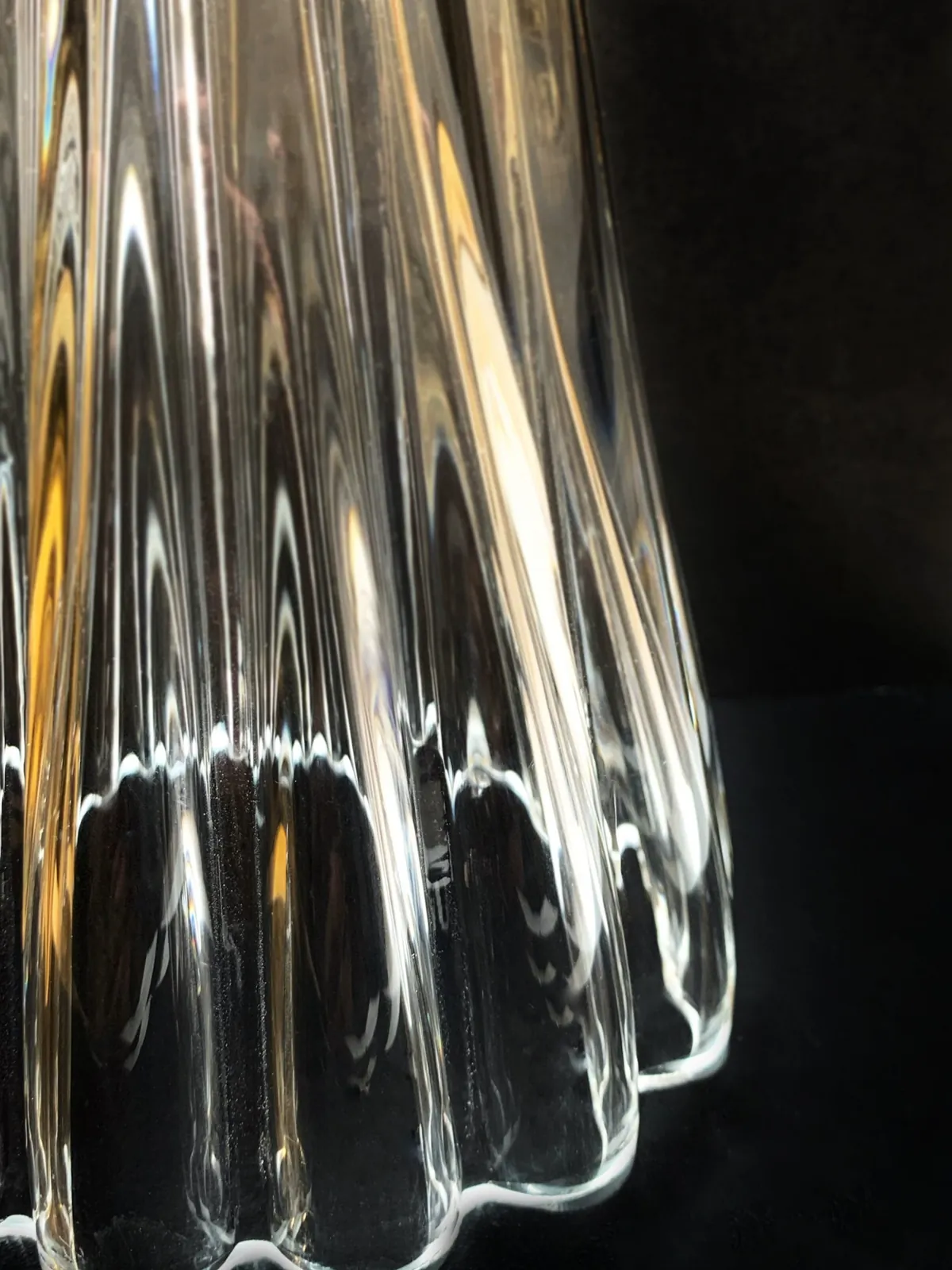 Macro di vetro soffiato trasparente, costolato, contro un fondo scuro.
